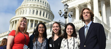 Five students, four women and one man, pose for a photo on the steps at the US Capitol