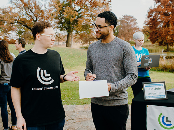 A CCL volunteer speaks to a member of the community at an outdoor tabling event