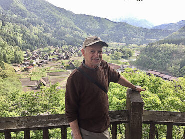 Donor Jim Lilienthal stands on a deck overlooking a lush green valley and foreign village