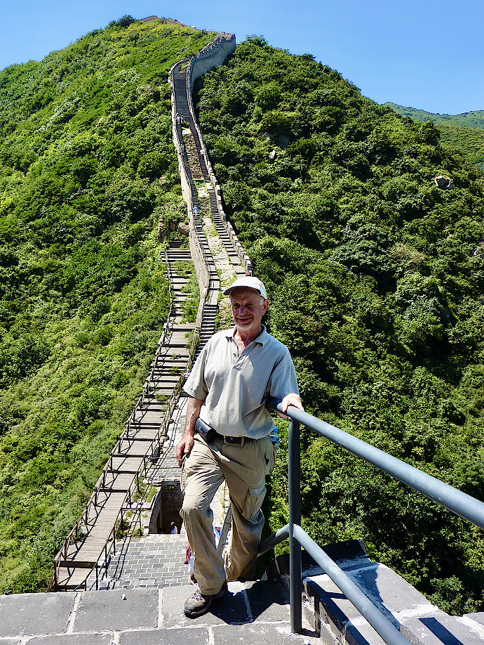 Donor Jim Lilienthal stands on the Great Wall of China. He is an older white man in a light colored baseball cap, shirt, and pants.