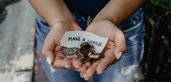 hands holding some pocket change and a written note with words "make a change"