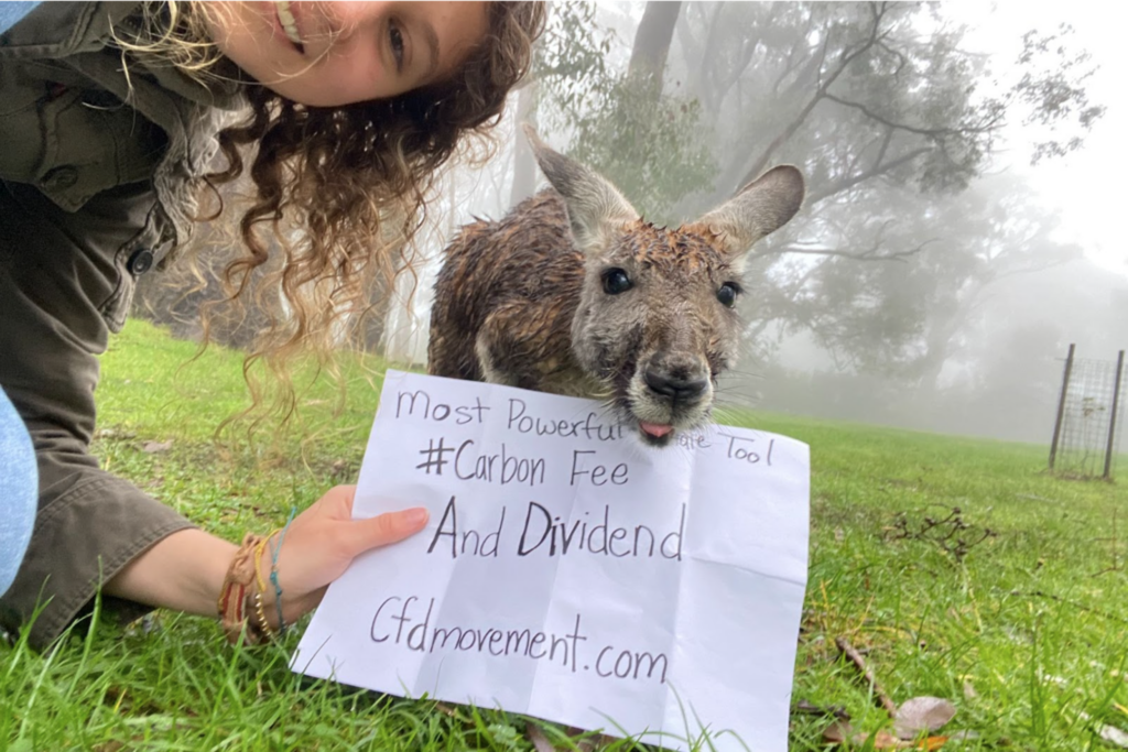 Woman posing with an animal holding a sign.