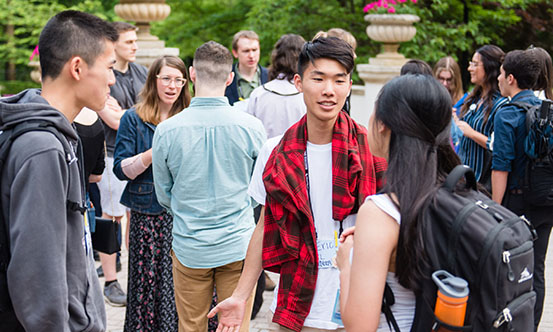 A group of college-age people talking outside at an event.
