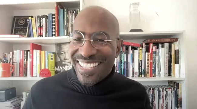 Van Jones, a bald Black man wearing glasses and a black turtleneck sweater, smiles broadly. His background is a colorful bookshelf, with books and several awards displayed.