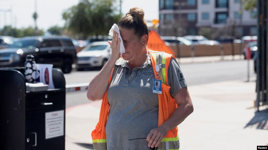Worker wipes her face with a wet rag while outside in 106° F heat in Phoenix, Arizona.