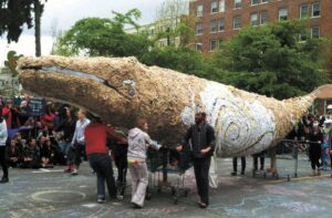 Image shows the full whale sculpture, with several people pushing it into place for display