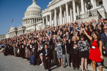 A large group of people cheers and celebrates on the steps of the U.S. Capitol