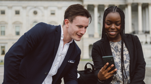 A young woman shows a young man something on her cell phone