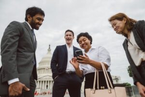Four CCLers gathered around a volunteer's mobile phone outside the U.S. Capitol building